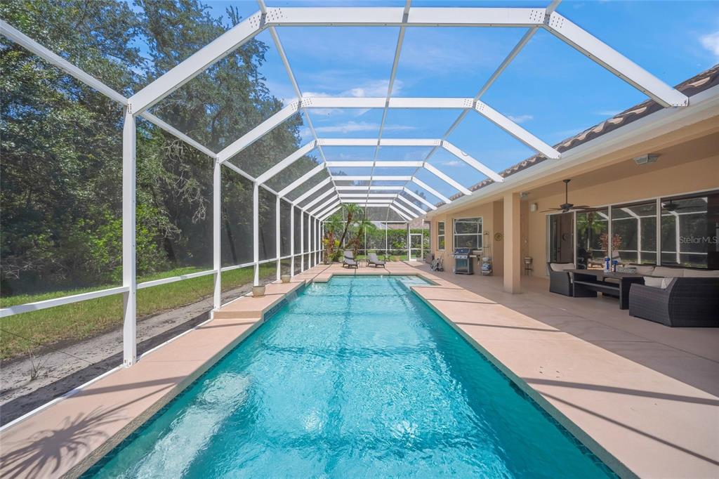 A screened-in swimming pool with a patio area and outdoor furniture under a covered lanai — 8488 EAGLE PRESERVE WAY, SARASOTA, FL