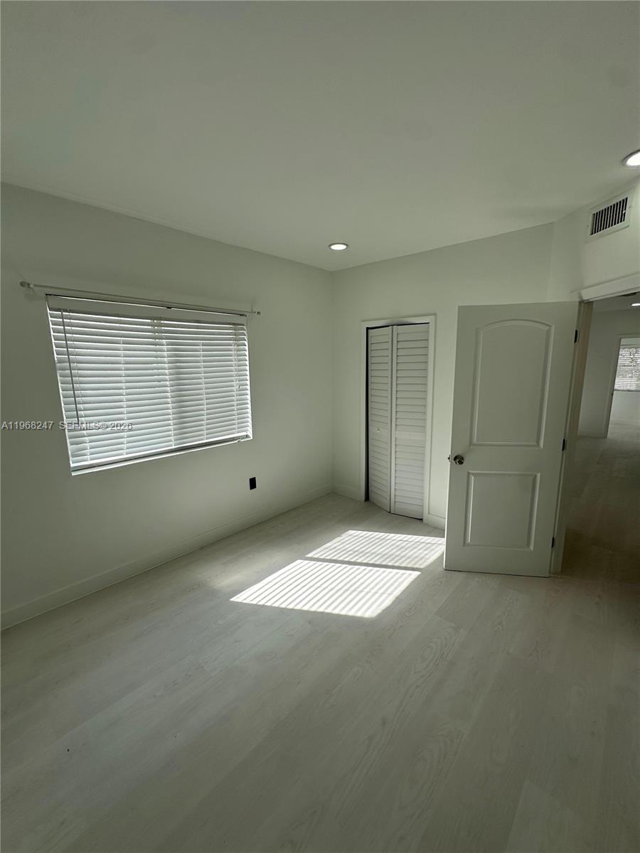 A bedroom features light-colored wood flooring, white walls, a window with blinds, and a closet — 109 NW 6th Ave # 5, Miami FL 33128, MIAMI, FL