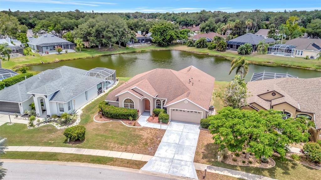 An aerial view shows a tan single-story house with a driveway facing a small lake — 4206 73RD TERRACE E, SARASOTA, FL
