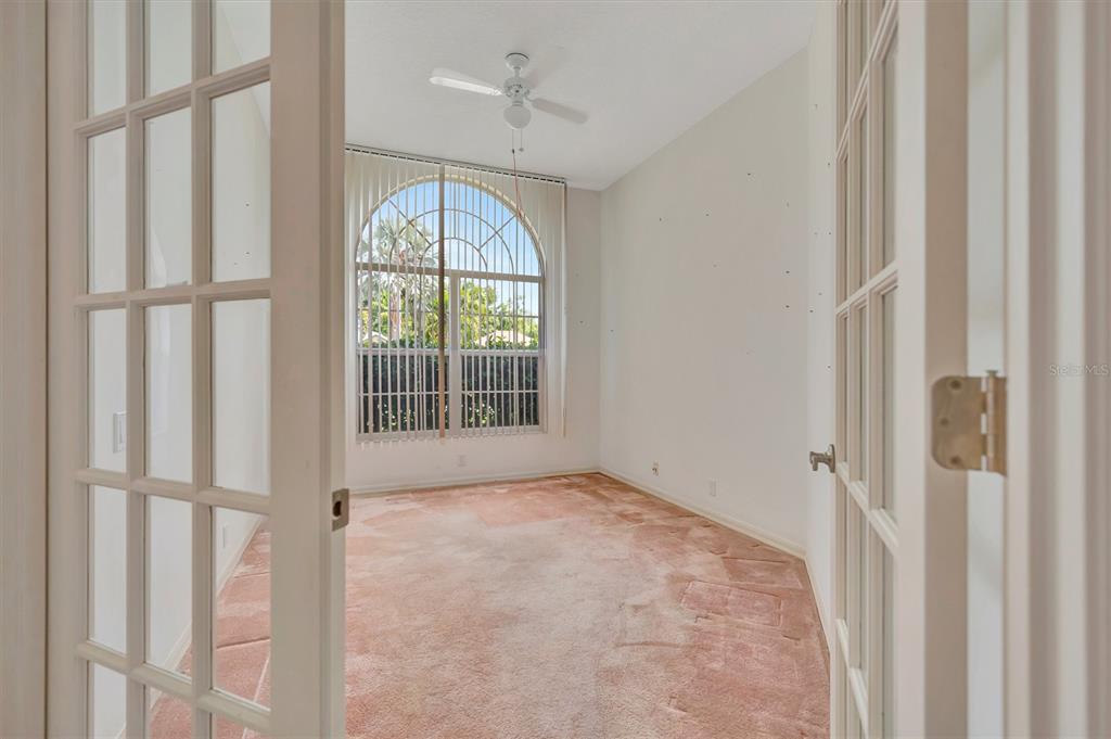 An empty room with beige carpet, white walls, a ceiling fan, and an arched window — 4206 73RD TERRACE E, SARASOTA, FL