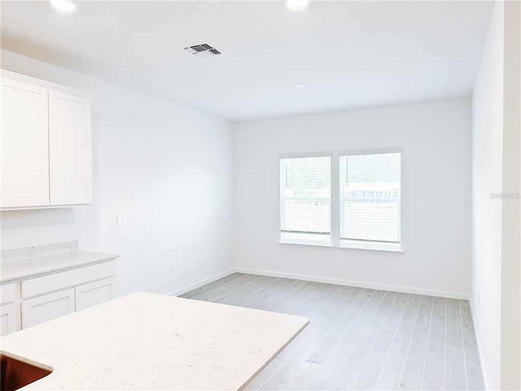 A bright kitchen dining area features white cabinets, quartz countertops, and light wood-look tile flooring — 6583 SW 89TH LOOP, OCALA, FL