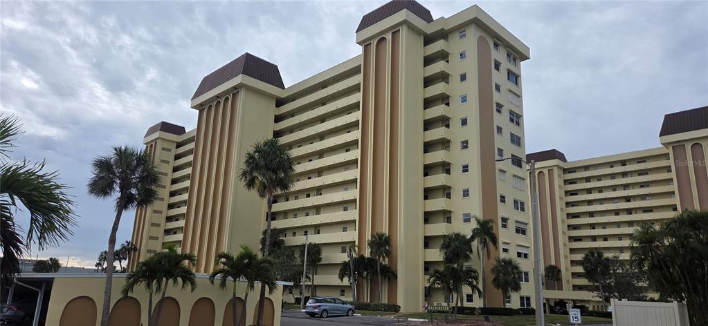 A multi-story beige apartment building with balconies and palm trees in the foreground — 4550 COVE CIRCLE UNIT 1205, ST PETERSBURG, FL