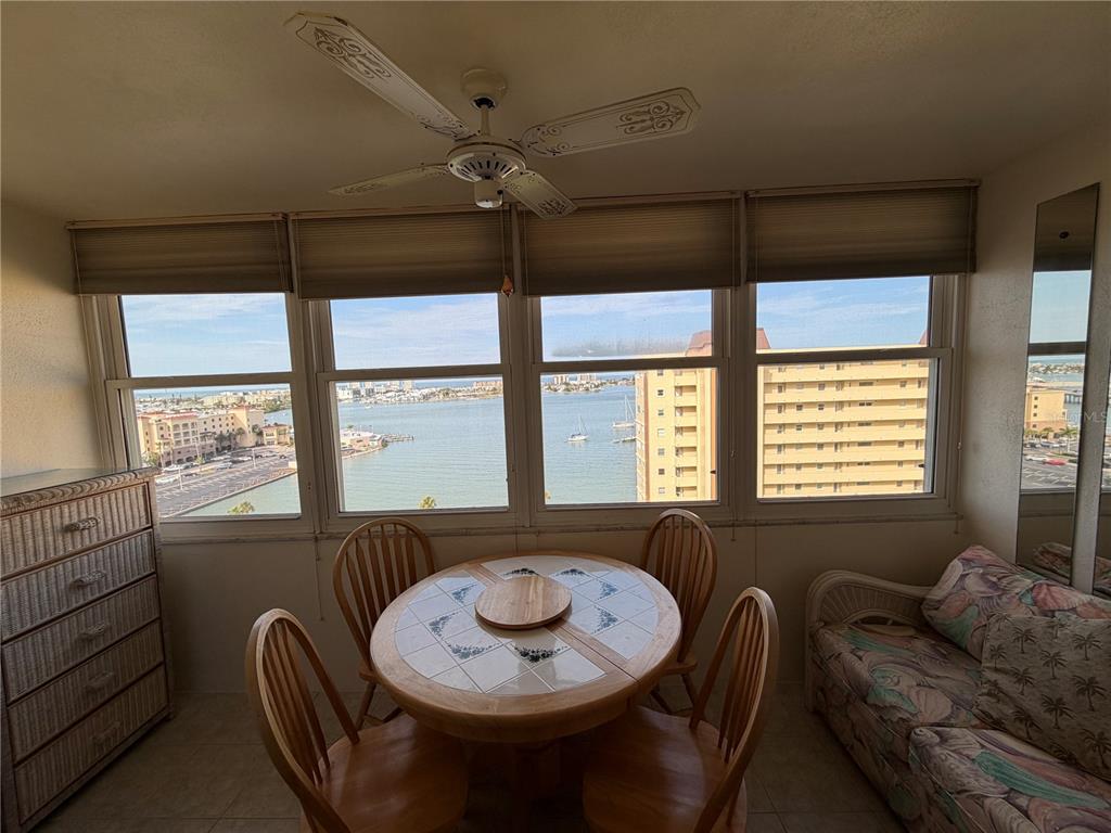 A dining area features a round tiled table, four wooden chairs, and large waterfront windows — 4550 COVE CIRCLE UNIT 1205, ST PETERSBURG, FL