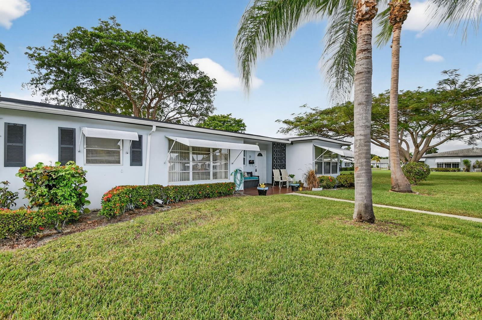 A single-story light blue house with a lawn, palm trees, and a small front porch — 615 High Point Drive # C, Delray Beach FL 33445, DELRAY BEACH, FL