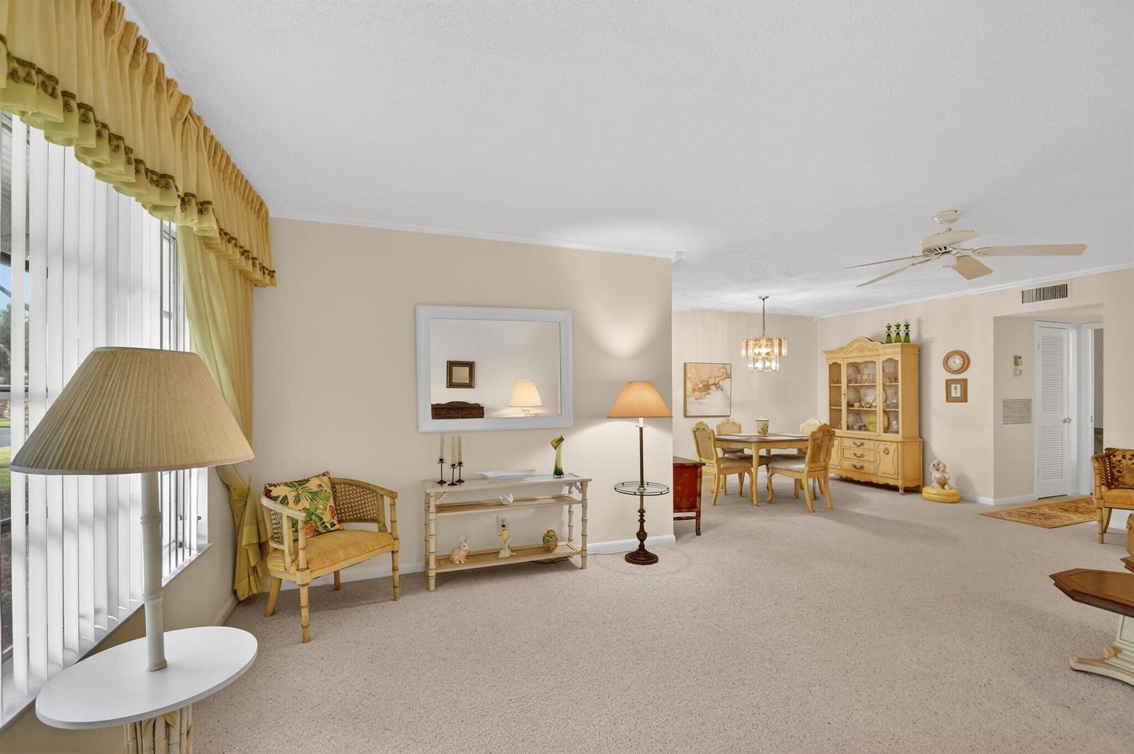 A living and dining area with beige carpeting, neutral walls, and traditional wooden furniture — 615 High Point Drive # C, Delray Beach FL 33445, DELRAY BEACH, FL