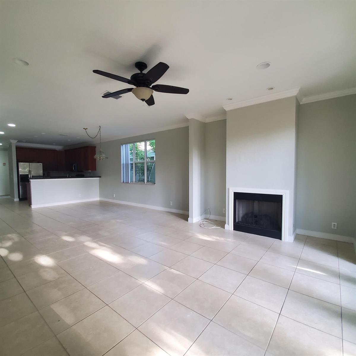 A spacious living room with light tile flooring, a fireplace, and an open kitchen — 115 Akron Street # C, FL 33461, FL