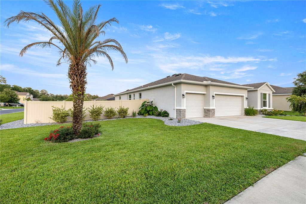A single-story house with a two-car garage, a palm tree, and a vinyl fence — 1927 NE 50TH COURT, OCALA, FL