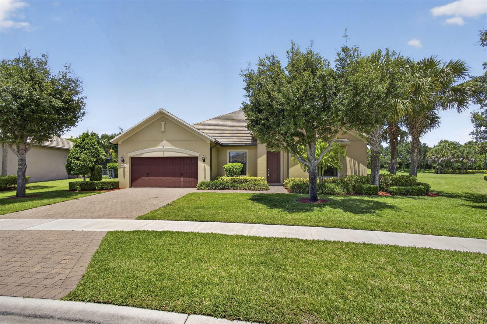 A single-story house with a tan stucco exterior, a brown garage door, and landscaped yard — 4023 Siena Circle, Wellington FL 33414, WELLINGTON, FL