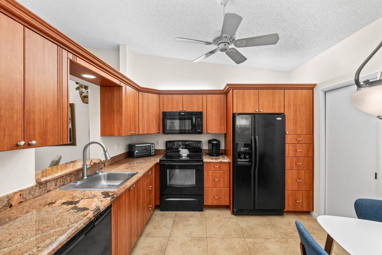 A single-story duplex with tan stucco walls, two white garage doors, and a landscaped lawn — 8286 Springlake Drive, Boca Raton FL 33496, BOCA RATON, FL