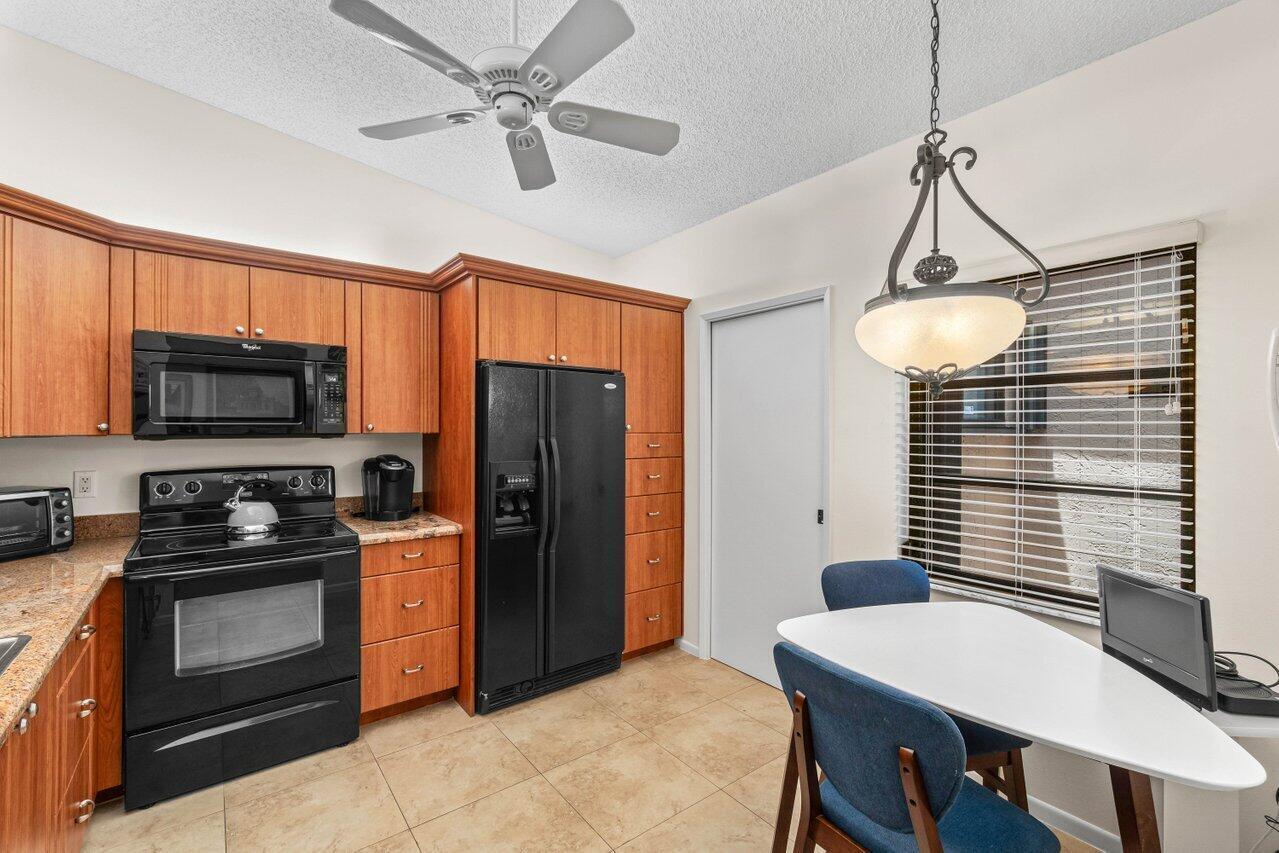 A wicker chair sits on a tiled patio next to a white front door — 8286 Springlake Drive, Boca Raton FL 33496, BOCA RATON, FL