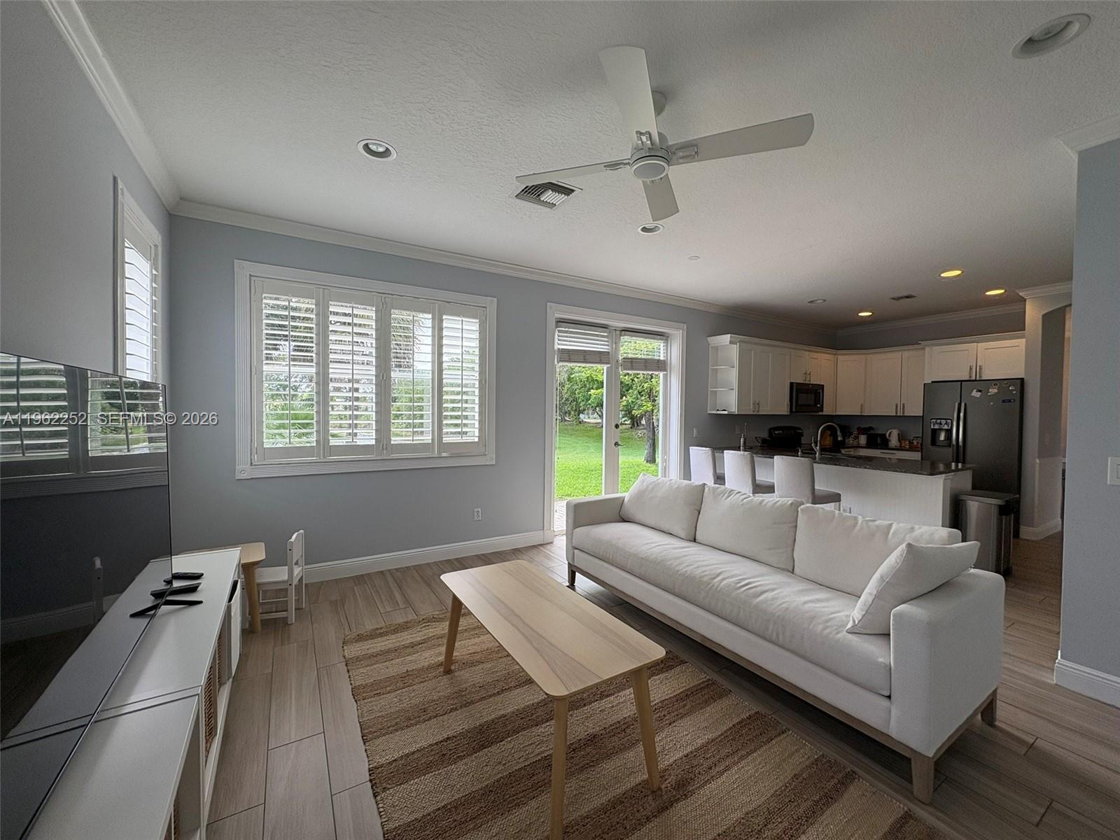 A living room with a white sofa, wood coffee table, and an open kitchen — 10793 Oak Bend Way, Wellington FL 33414, WELLINGTON, FL