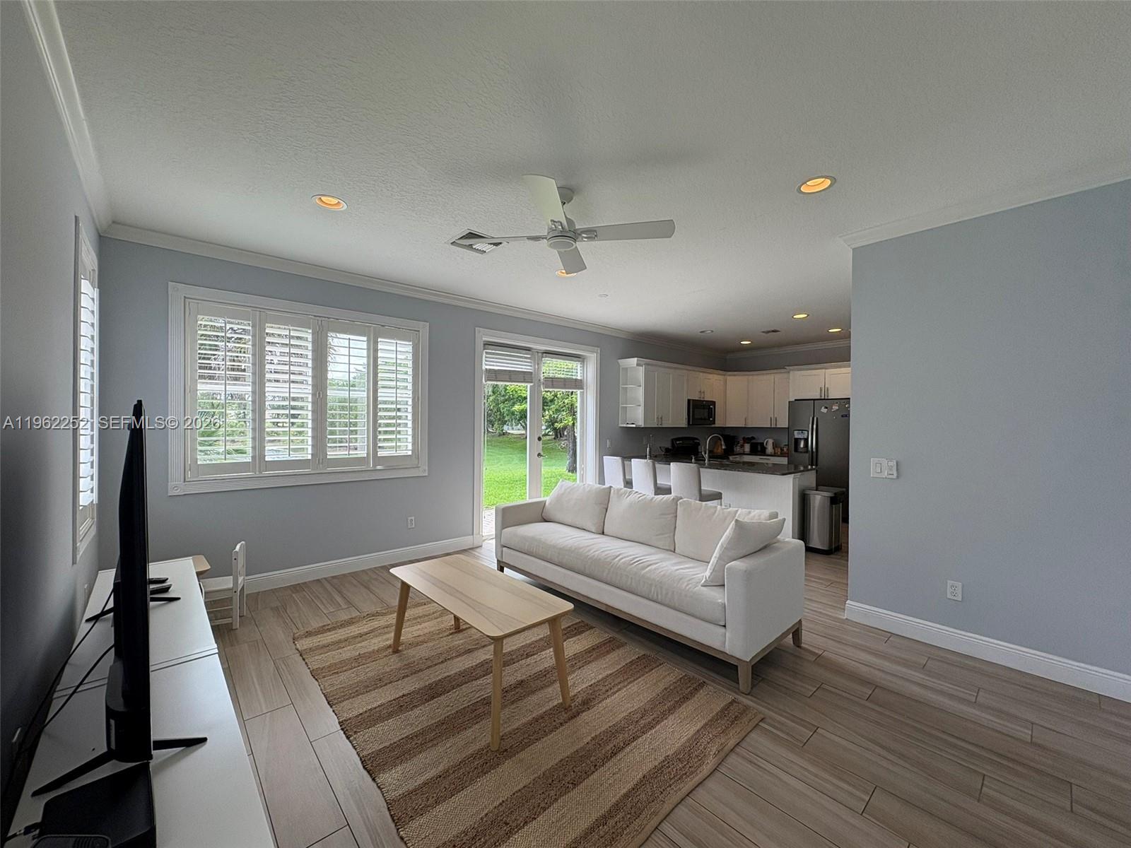 A living room with a white sofa, coffee table, and an open kitchen in the background — 10793 Oak Bend Way, Wellington FL 33414, WELLINGTON, FL