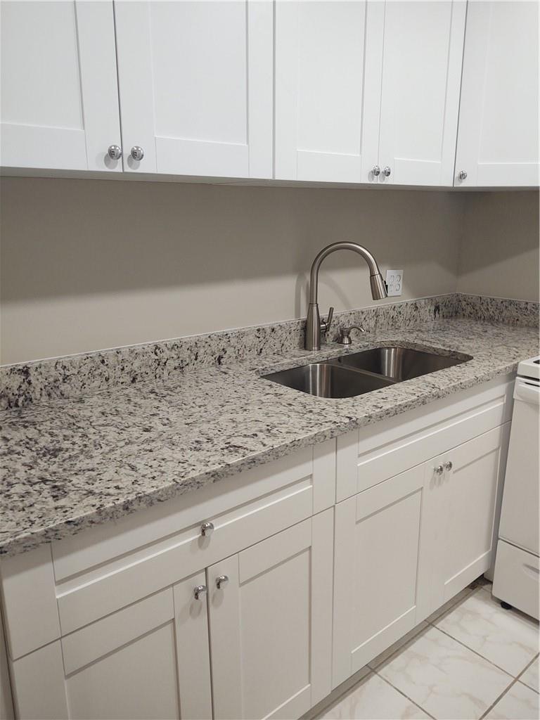 A kitchen features white shaker cabinets, granite countertops, and a stainless steel double-basin sink — 16 Keswick A # 16, Deerfield Beach FL 33442, DEERFIELD BEACH, FL