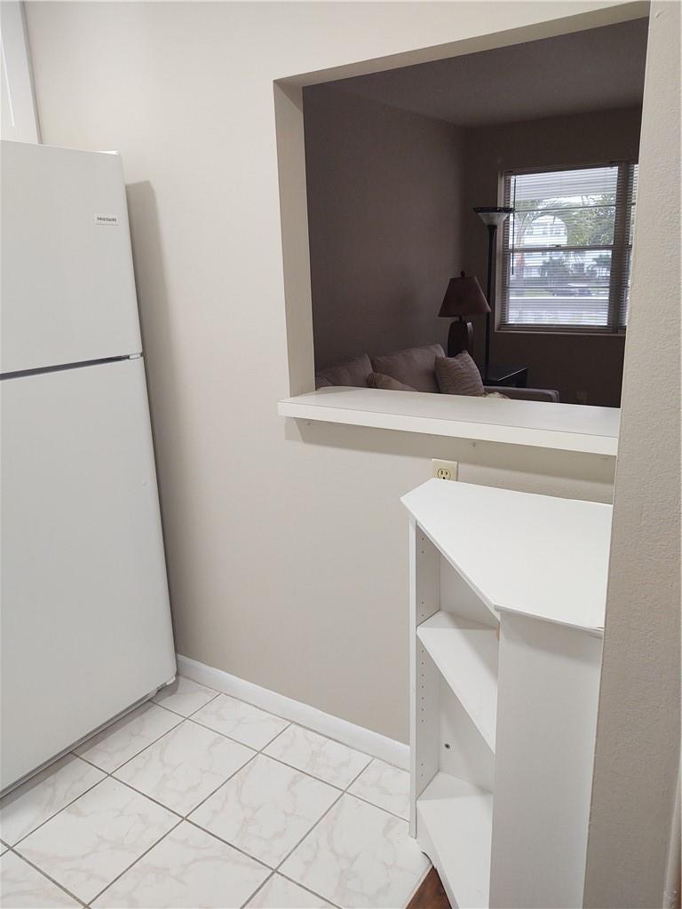 A kitchen area features a white refrigerator, a pass-through window, and a white corner shelf — 16 Keswick A # 16, Deerfield Beach FL 33442, DEERFIELD BEACH, FL