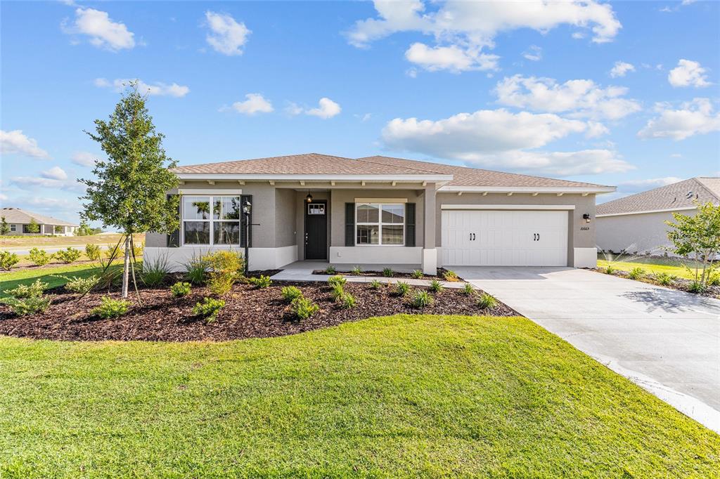 A single-story suburban house features a two-car garage, a covered entryway, and landscaped front yard — 10665 SW 101ST LANE ROAD, OCALA, FL
