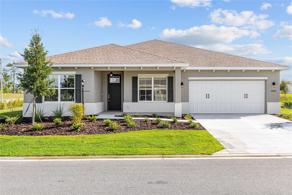A single-story house with a gray stucco exterior, a two-car garage, and a shingled roof — 10665 SW 101ST LANE ROAD, OCALA, FL