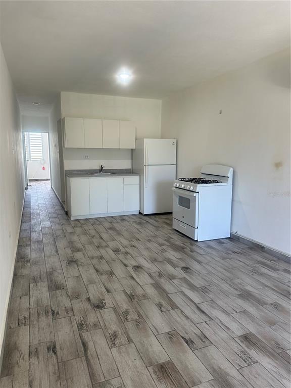 A kitchen area features white cabinets, a refrigerator, a gas stove, and wood-look tile flooring — Calle 12 2874 CALLE 12, RINCON, PR