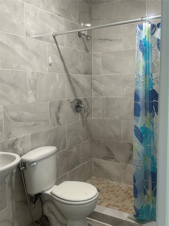 A bathroom features a tiled walk-in shower with a curtain and a white toilet — Calle 12 2874 CALLE 12, RINCON, PR