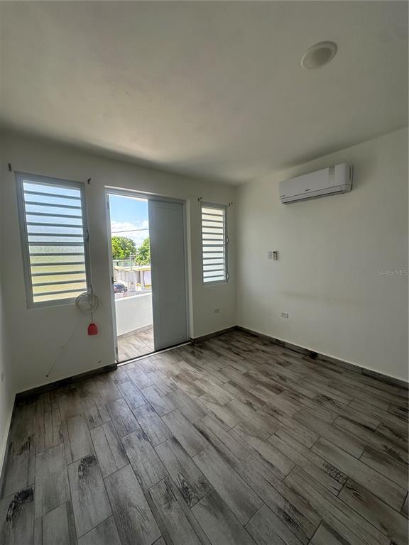 An empty room features wood-look tile flooring, a glass door to a balcony, and air conditioning — Calle 12 2874 CALLE 12, RINCON, PR