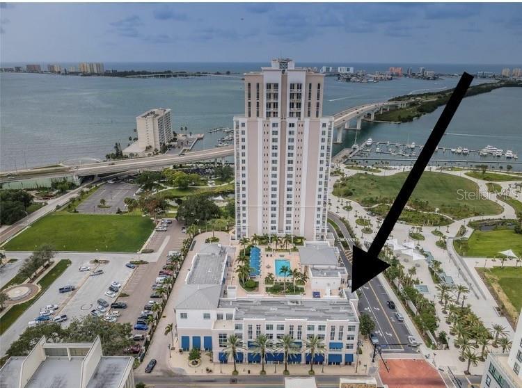 An aerial view shows a tall residential tower with a pool deck and surrounding parkland — 331 CLEVELAND STREET UNIT 310, CLEARWATER, FL