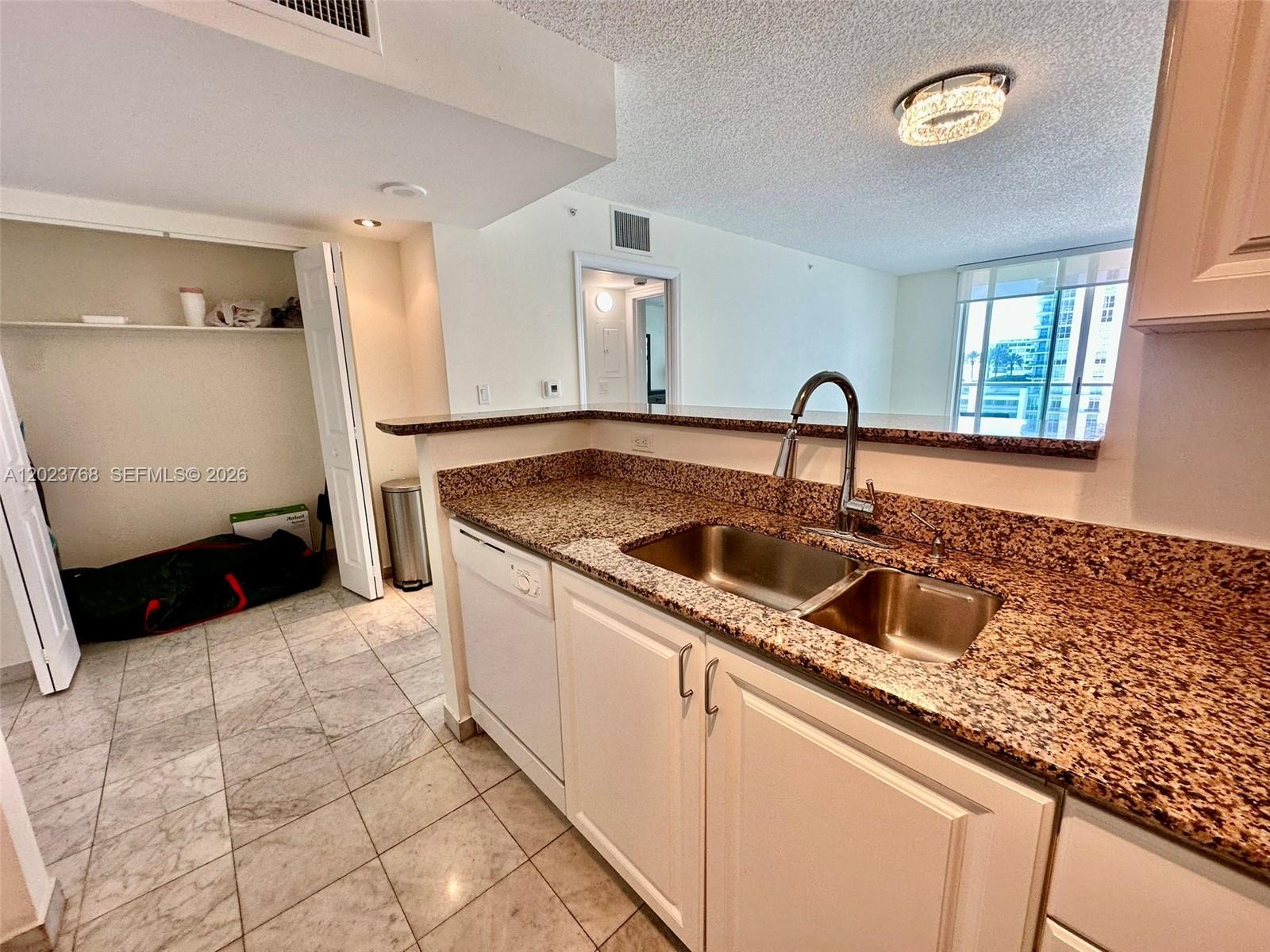 A kitchen features white cabinets, granite countertops, a double sink, and tile flooring — 1155 Brickell Bay Dr # 905, Miami FL 33131, MIAMI, FL