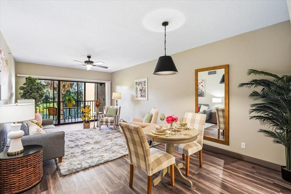 A living and dining area features wood-look flooring, a ceiling fan, and a sliding glass door — 4540 BEE RIDGE ROAD UNIT 175, SARASOTA, FL