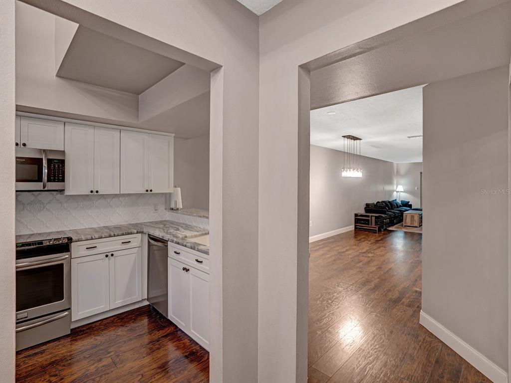 A kitchen with white cabinets and stainless steel appliances opens into a living room area — 2511 DOLLY BAY DRIVE UNIT 308, PALM HARBOR, FL