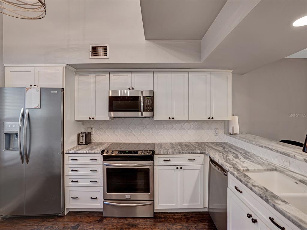 A kitchen features white cabinets, stainless steel appliances, and gray marble-patterned countertops — 2511 DOLLY BAY DRIVE UNIT 308, PALM HARBOR, FL