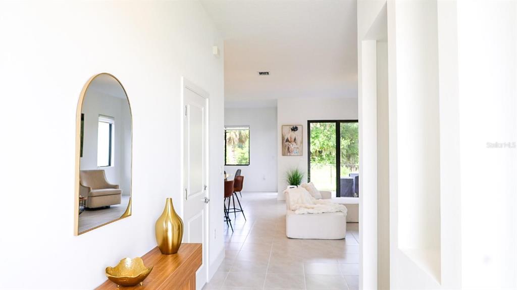 A bright entryway leads to an open-concept living area with tile floors and modern decor — 5868 AGOSTINO WAY, IMMOKALEE, FL