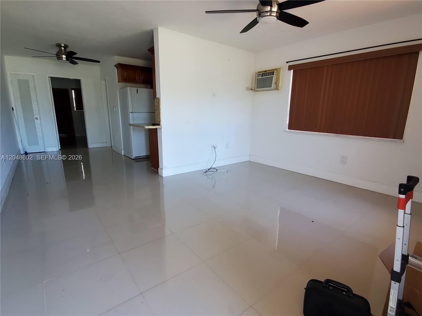 An unfurnished living room features light tile flooring, a ceiling fan, and a window unit — 808 N 24th Ave # 1, Hollywood FL 33020, HOLLYWOOD, FL