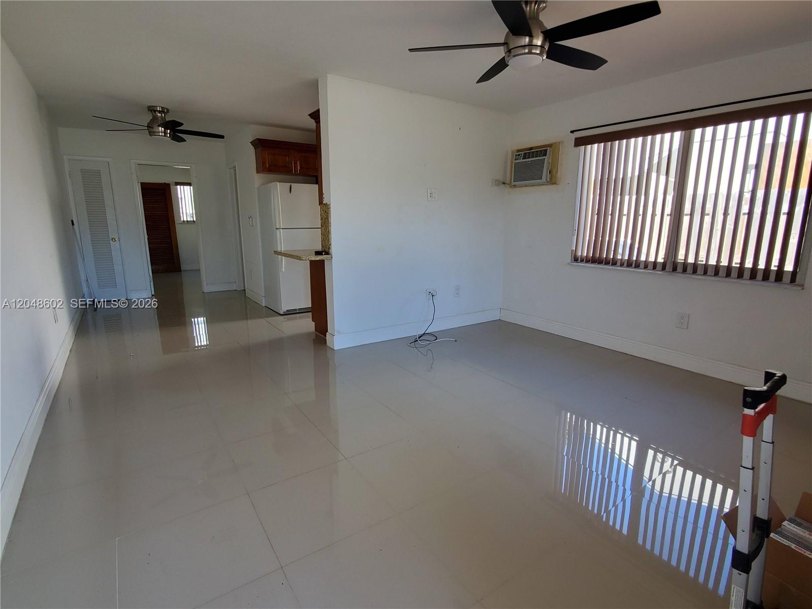 An open-concept living area features white tile floors, a ceiling fan, and a kitchen corner — 808 N 24th Ave # 1, Hollywood FL 33020, HOLLYWOOD, FL