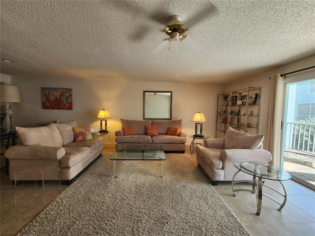 A living room features a beige sofa set, a glass coffee table, and a shag rug — 1101 PINELLAS BAYWAY S UNIT 303, TIERRA VERDE, FL