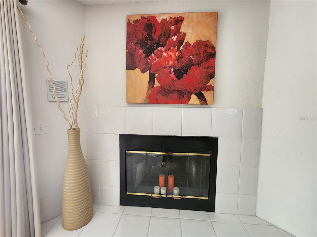 A fireplace with white tile surround and a large floral painting sits in a room — 1101 PINELLAS BAYWAY S UNIT 303, TIERRA VERDE, FL