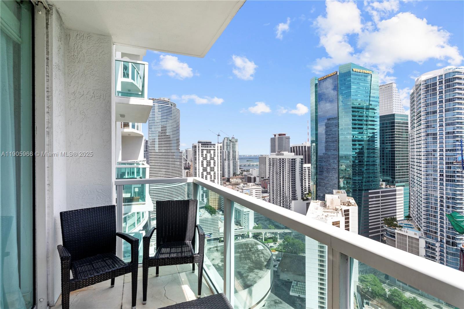 A balcony with two black chairs overlooks a dense city skyline with several skyscrapers — 31 SE 5th St # 4018, Miami FL 33131, MIAMI, FL