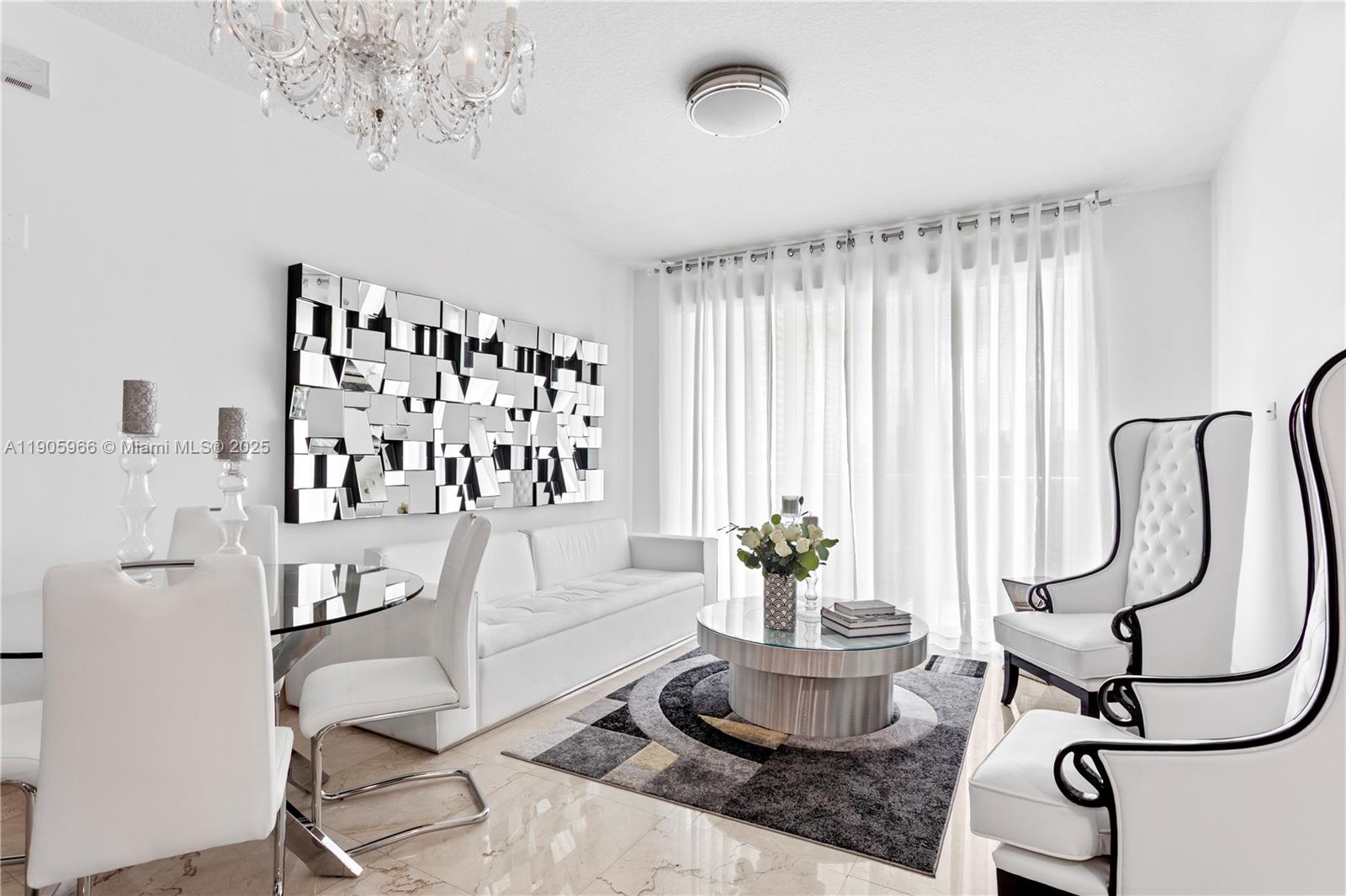 A modern living and dining area features white furniture, a geometric mirror, and a chandelier — 31 SE 5th St # 4018, Miami FL 33131, MIAMI, FL