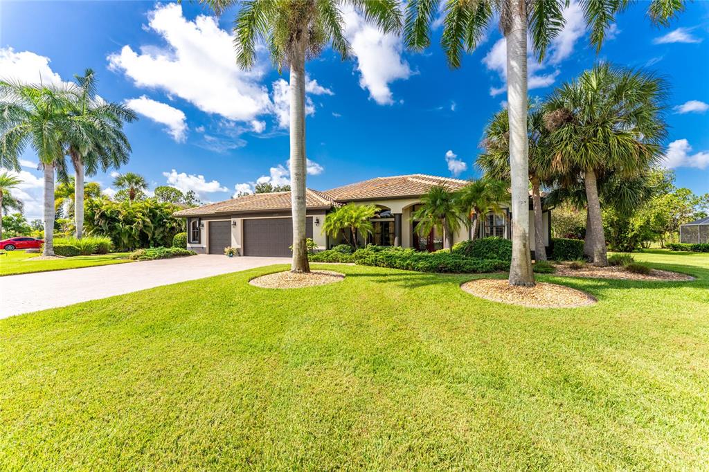 A single-story house with a tile roof, three-car garage, and palm trees on a lawn — 25279 PUNTA MADRYN AVENUE, PUNTA GORDA, FL