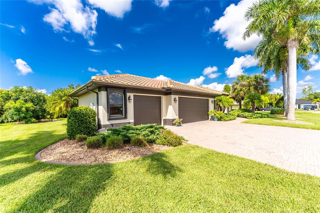 A single-story house with a tiled roof, two garage doors, and a paved driveway — 25279 PUNTA MADRYN AVENUE, PUNTA GORDA, FL