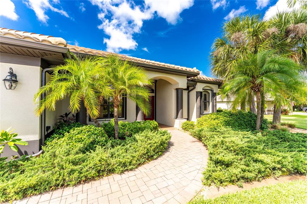 A paved walkway leads to the front entrance of a house with palm trees — 25279 PUNTA MADRYN AVENUE, PUNTA GORDA, FL
