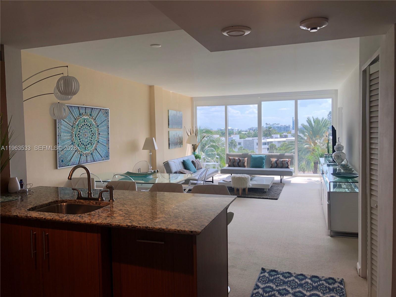 A kitchen with granite countertops overlooks a living room with floor-to-ceiling windows and city views — 10275 Collins Ave # 427, Bal Harbour FL 33154, BAL HARBOUR, FL