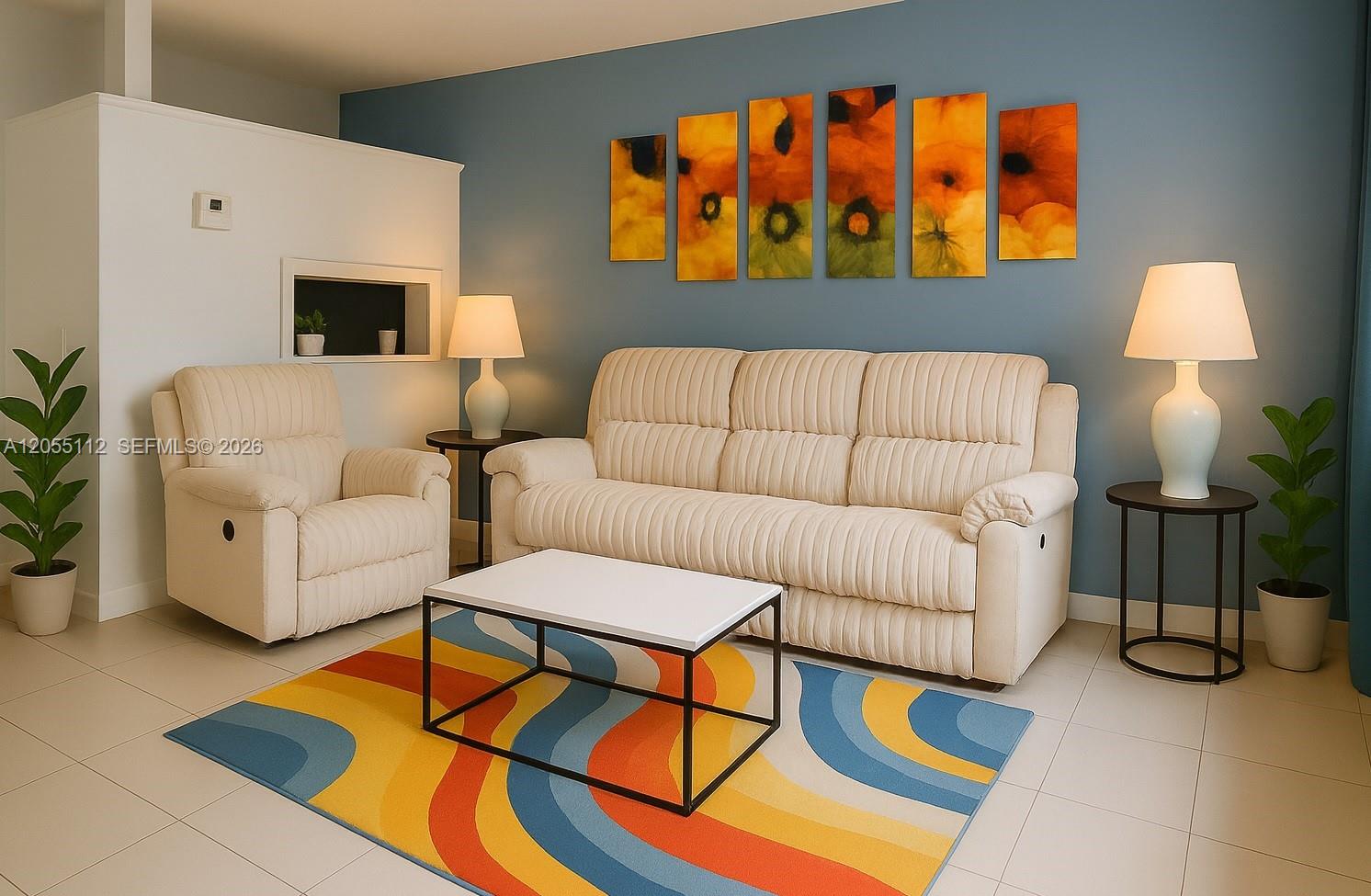A living room features a beige sofa and armchair, a colorful rug, and wall art — 901 SW 11th Ave # 4H, Hallandale Beach FL 33009, HALLANDALE BEACH, FL