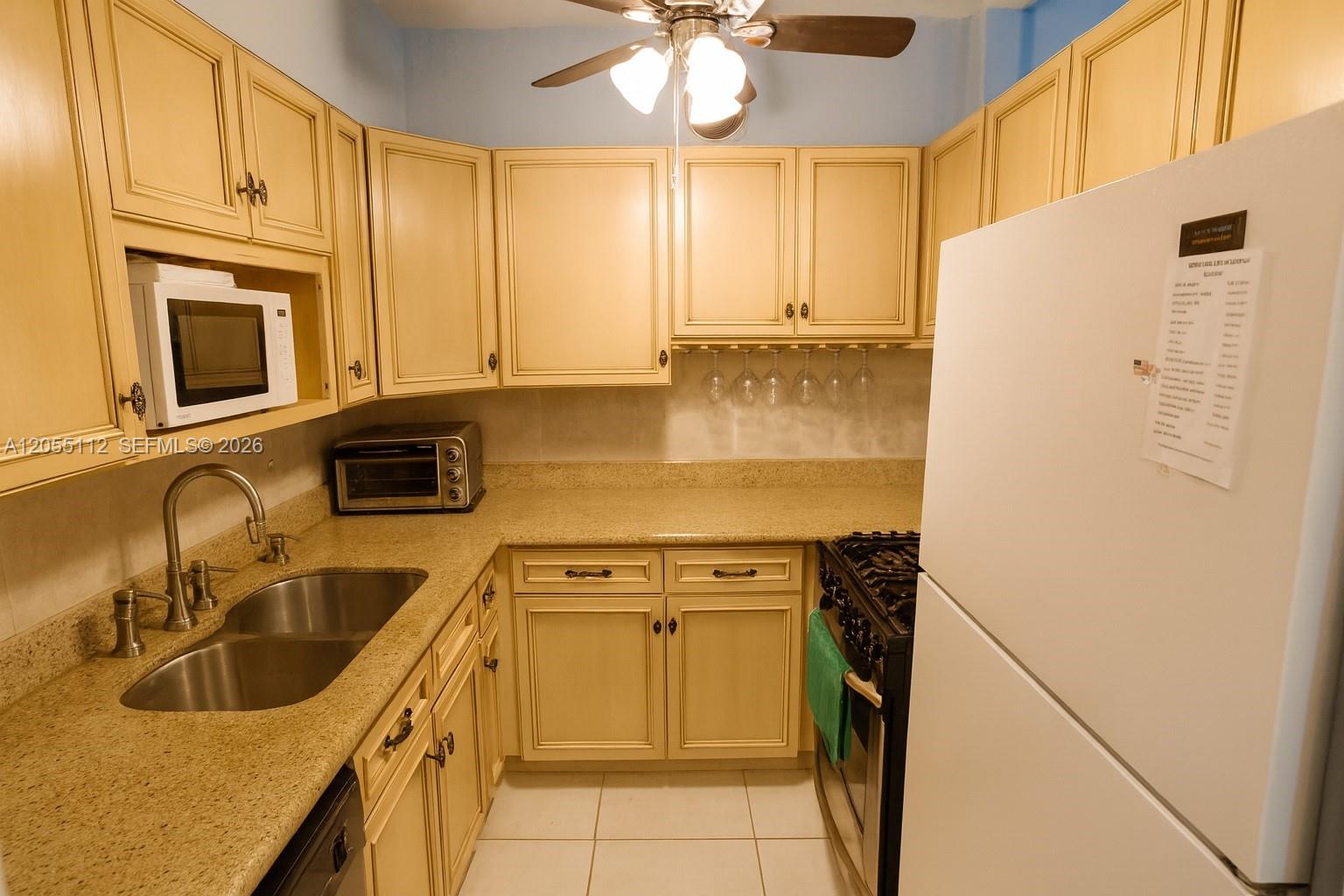 A small kitchen features light-colored cabinets, granite countertops, a double sink, and white appliances — 901 SW 11th Ave # 4H, Hallandale Beach FL 33009, HALLANDALE BEACH, FL