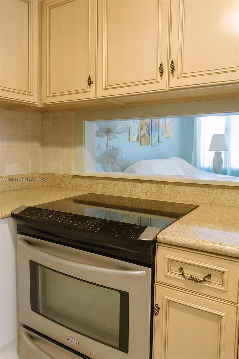 A stainless steel stove is set into a beige countertop beneath cream-colored kitchen cabinets — 901 SW 11th Ave # 4H, Hallandale Beach FL 33009, HALLANDALE BEACH, FL