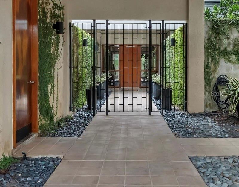 A paved walkway leads through a metal gate toward a wooden front door — 111 SAND PINE LANE, LONGWOOD, FL