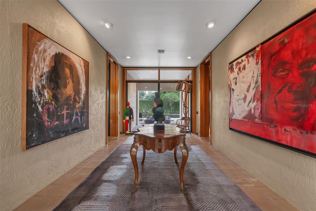 A hallway features a wooden console table, a patterned rug, and large paintings on walls — 111 SAND PINE LANE, LONGWOOD, FL