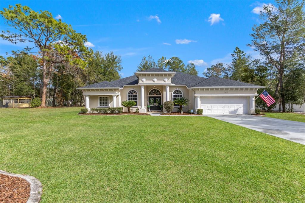 A single-story beige house with a multi-car garage and a large front lawn — 14071 LINDEN DRIVE, SPRING HILL, FL