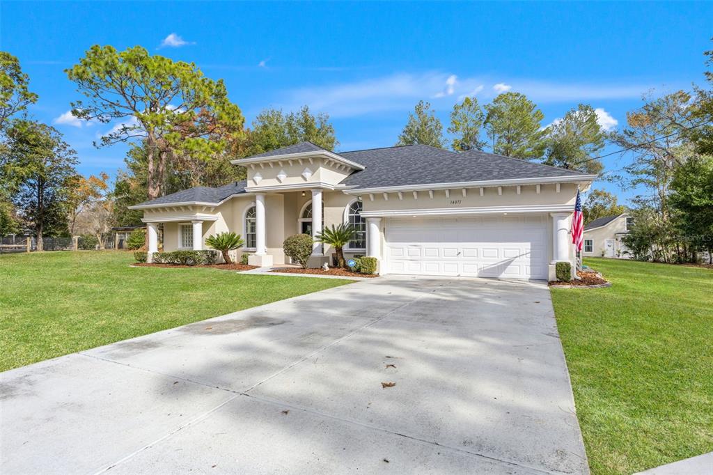 A single-story house with a white garage, columns, and a large front lawn — 14071 LINDEN DRIVE, SPRING HILL, FL