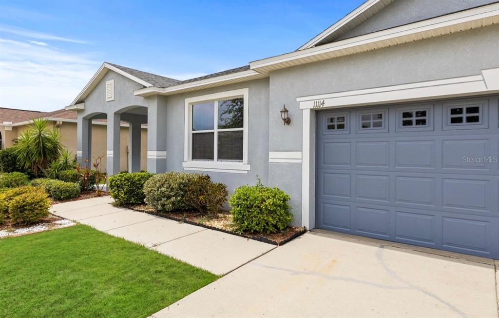 A light gray single-story house features a blue garage door and a concrete walkway — 11114 HARTFORD FERN DRIVE, RIVERVIEW, FL