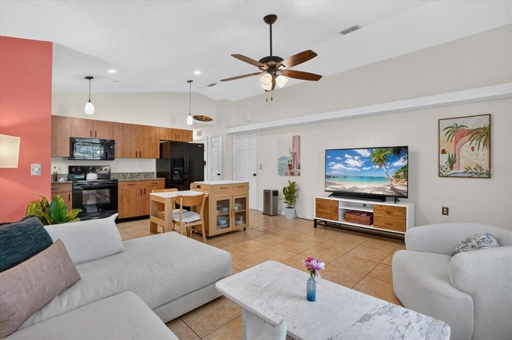 A living room with tile floors, a ceiling fan, and an open kitchen with wood cabinets — 5109 17TH AVENUE S, GULFPORT, FL