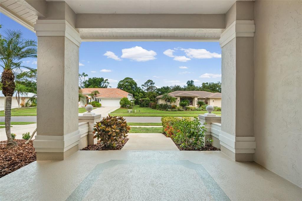 A view from a covered front porch looking out toward a suburban street and houses — 1318 VERMEER DRIVE, NOKOMIS, FL