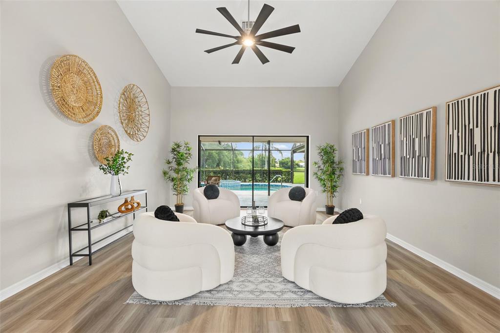A living room features four white curved chairs, a round coffee table, and pool views — 1318 VERMEER DRIVE, NOKOMIS, FL